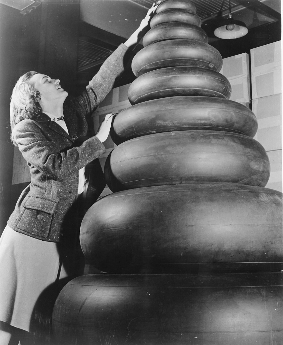 Woman standing next to a wide range of tire sizes required by military aircraft 